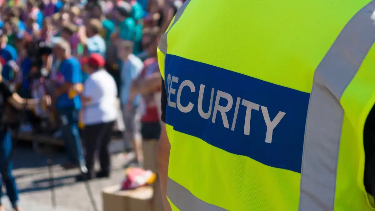Macroeconomic Slowdowns and the Security Guard Industry 2026 Outlook Macroeconomic Slowdowns and the Security Guard Industry: 2026 Outlook – A security guard monitors a crowded outdoor event, ensuring safety amid large gatherings.